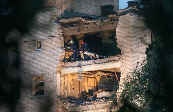 Záchranárov možno vidieť v osvetlených ruinách poškodenej budovy.
